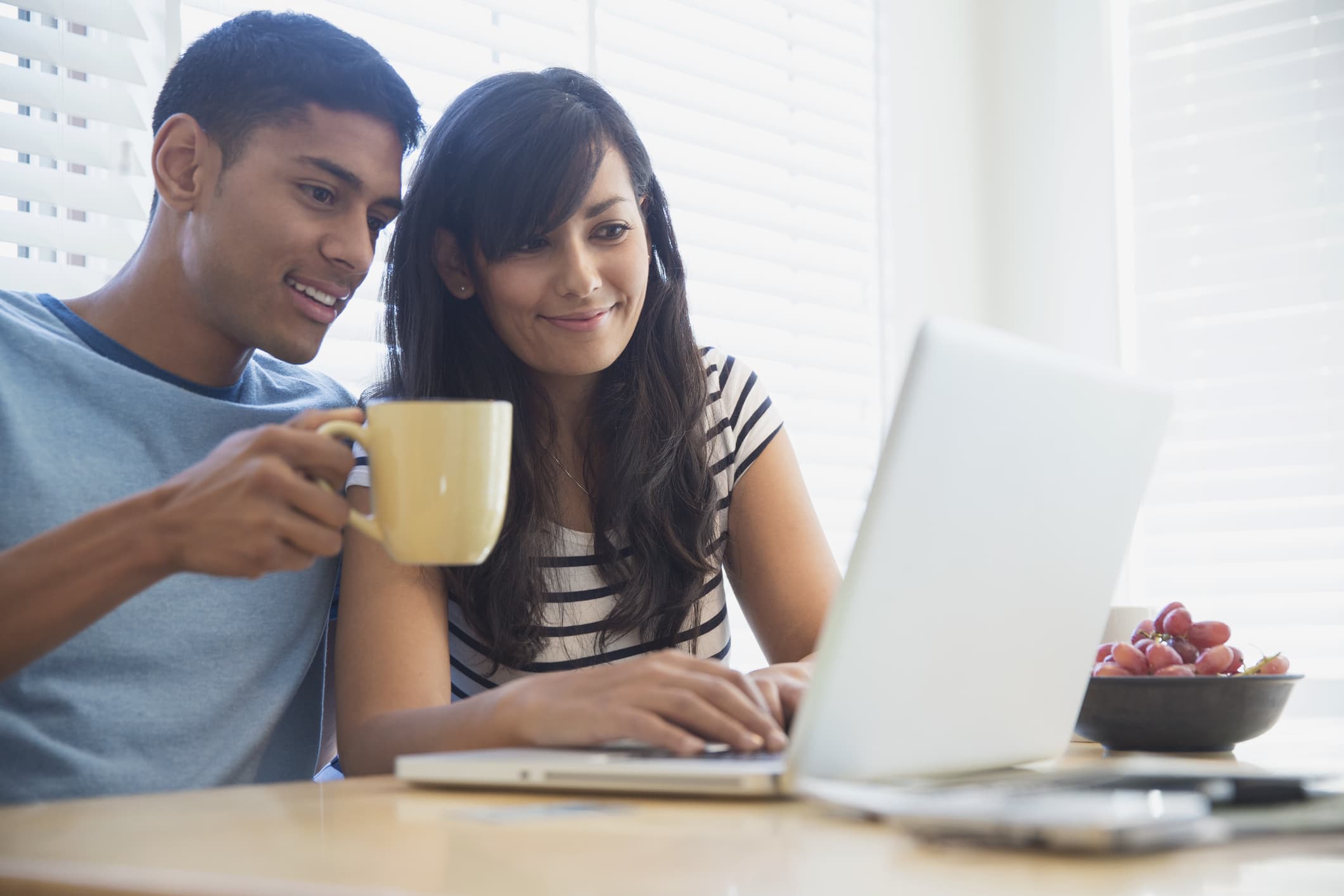 Couple using laptop together at breakfast table